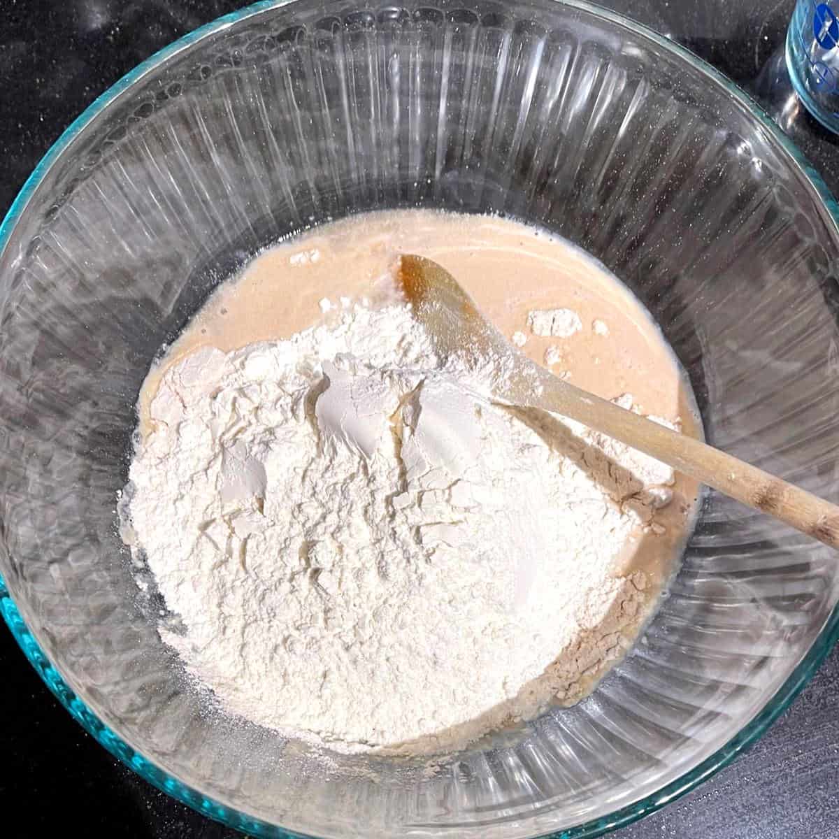 Flour added to bowl with yeast and water.