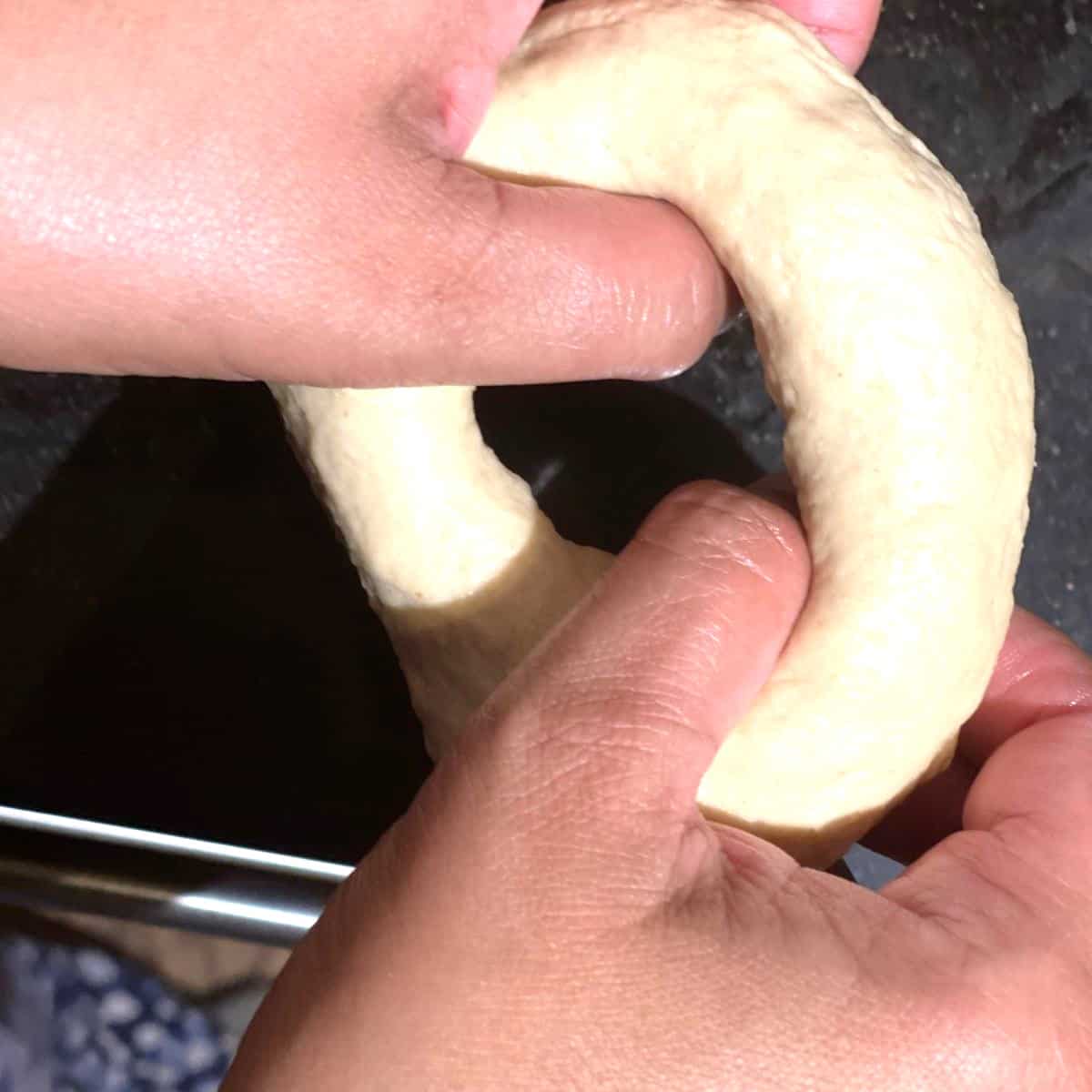 Bagel hole being shaped by hand.