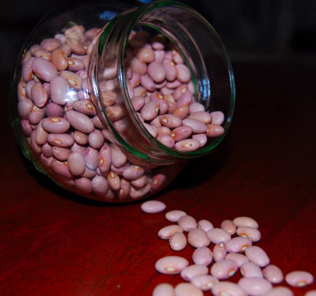Pink beans spilling out of a glass jar