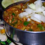 Usal, a spicy Indian bean curry, in a steel bowl with onions and limes