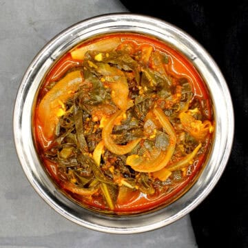 Kashmiri collard greens or haak saag in copper and steel bowl.