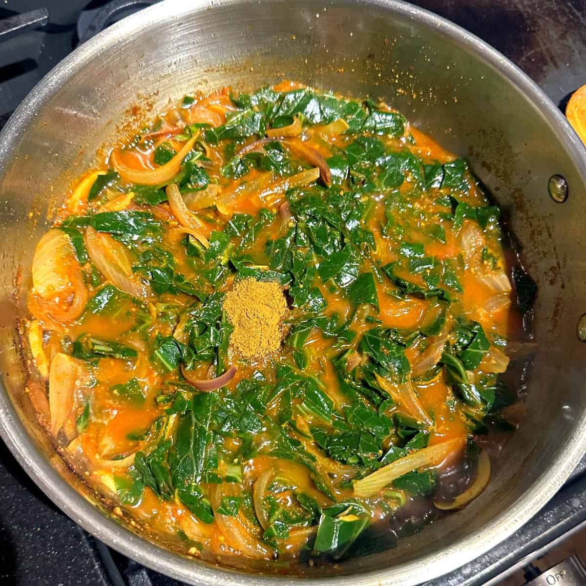 Garam masala added to pan with Kashmiri collard greens.
