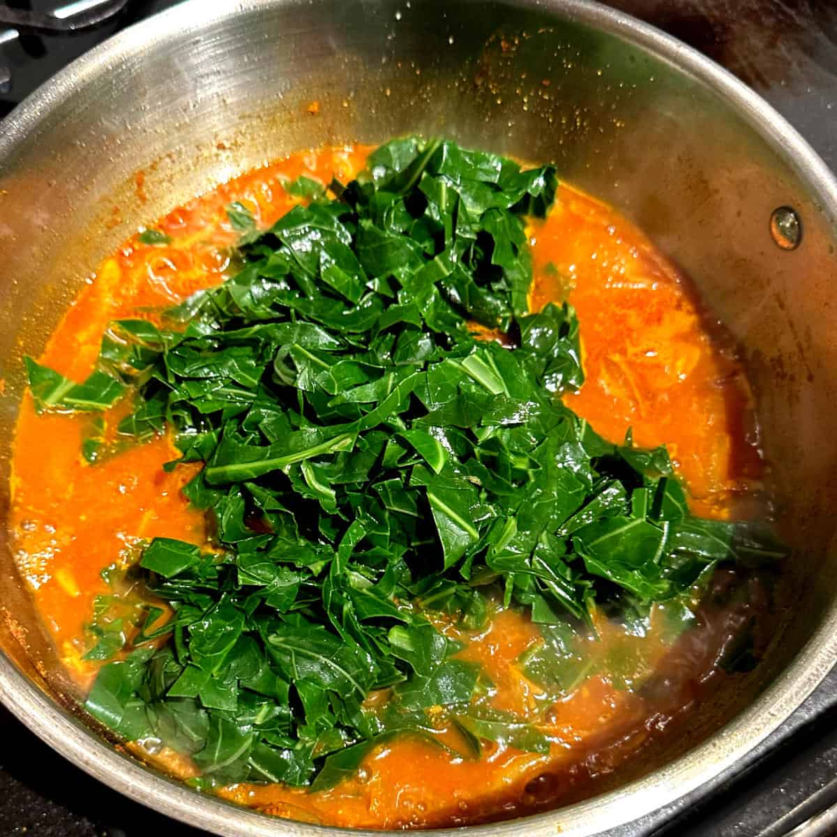 Collard greens added to pan with tomatoes, onions and spices.