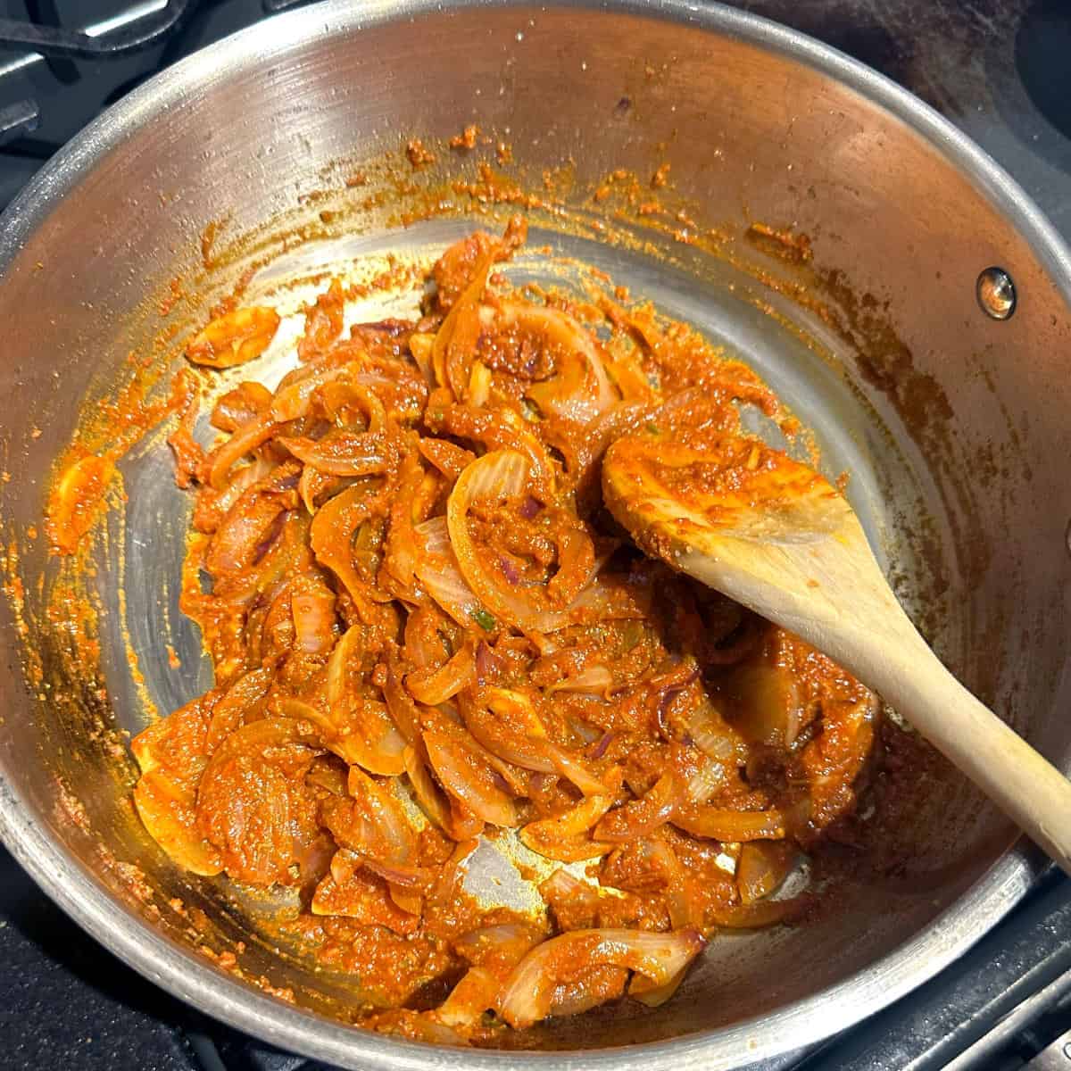 Spices and onions and tomatoes mixed in pan, cooking.