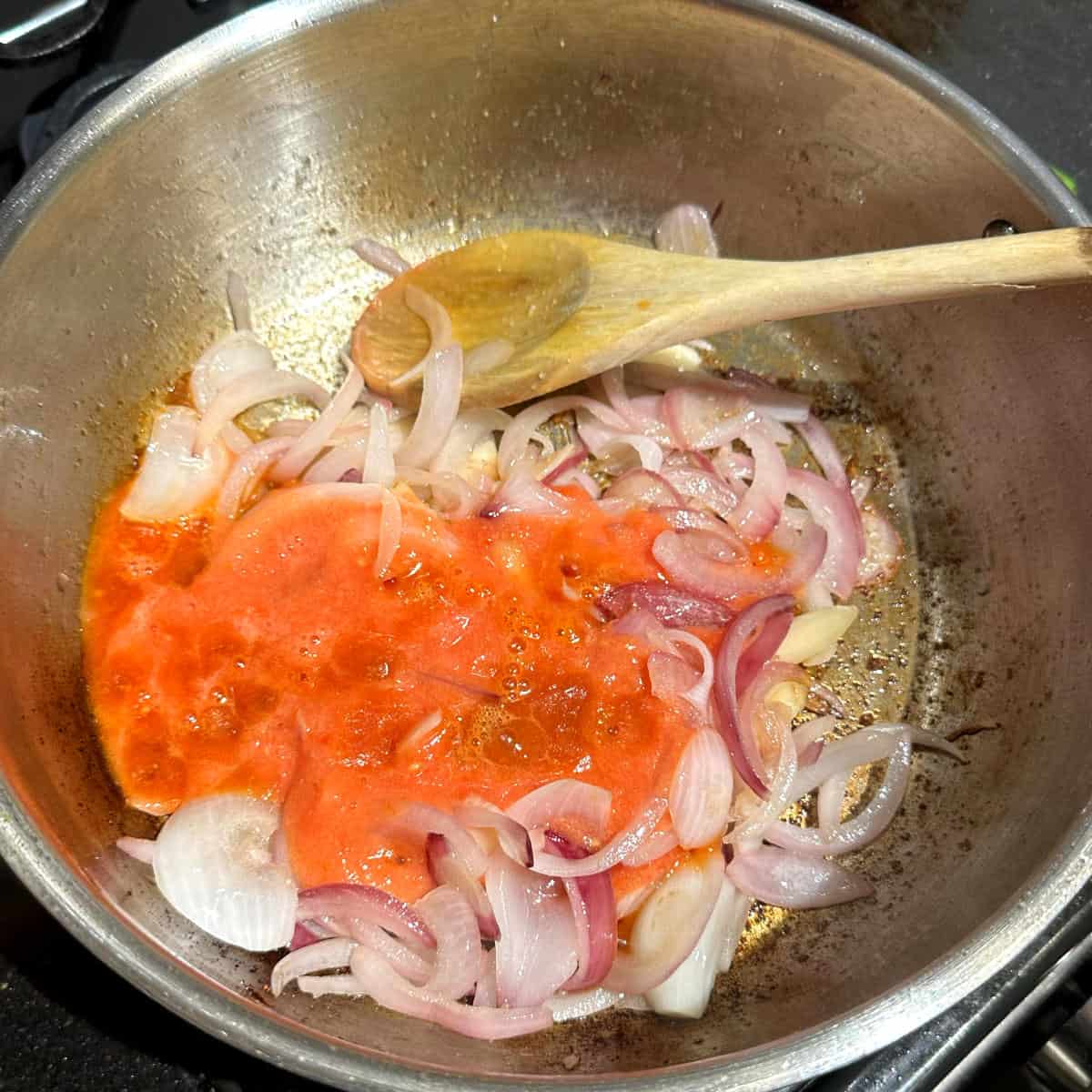 Tomato puree added to pan with onions and garlic.
