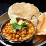 Chole Bhatura or Chana Bhatura is a North Indian dish to die for. A spicy, traditional chana masala is served with a puffy, flaky bread called a Bhatura. You might be lucky enough to find this specialty, usually served at roadside eateries called dhabas in India, at an Indian restaurant. The chana masala is gluten-free. #vegan #soyfree #nutfree #glutenfree #dinner #indian HolyCowVegan.net