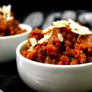 Partial shot of a bowl filled with gajar ka halwa and sliced almonds