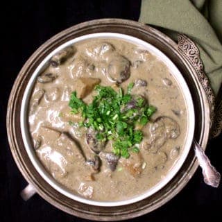 Malaysian mushroom korma in white bowl with cilantro garnish and spoon.