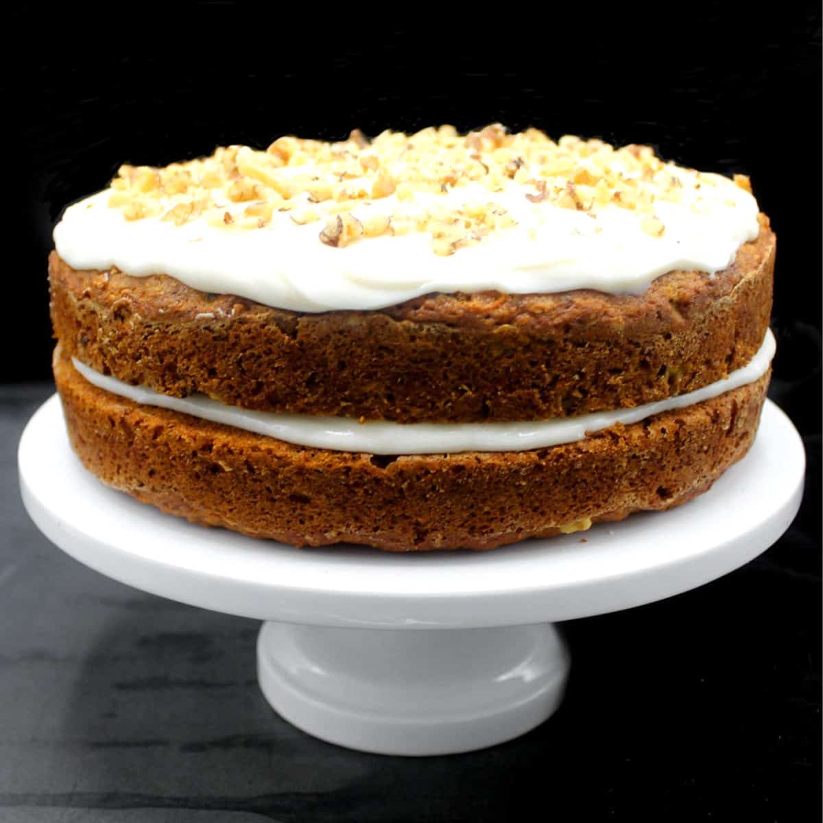 Vegan carrot cake on white cake stand.