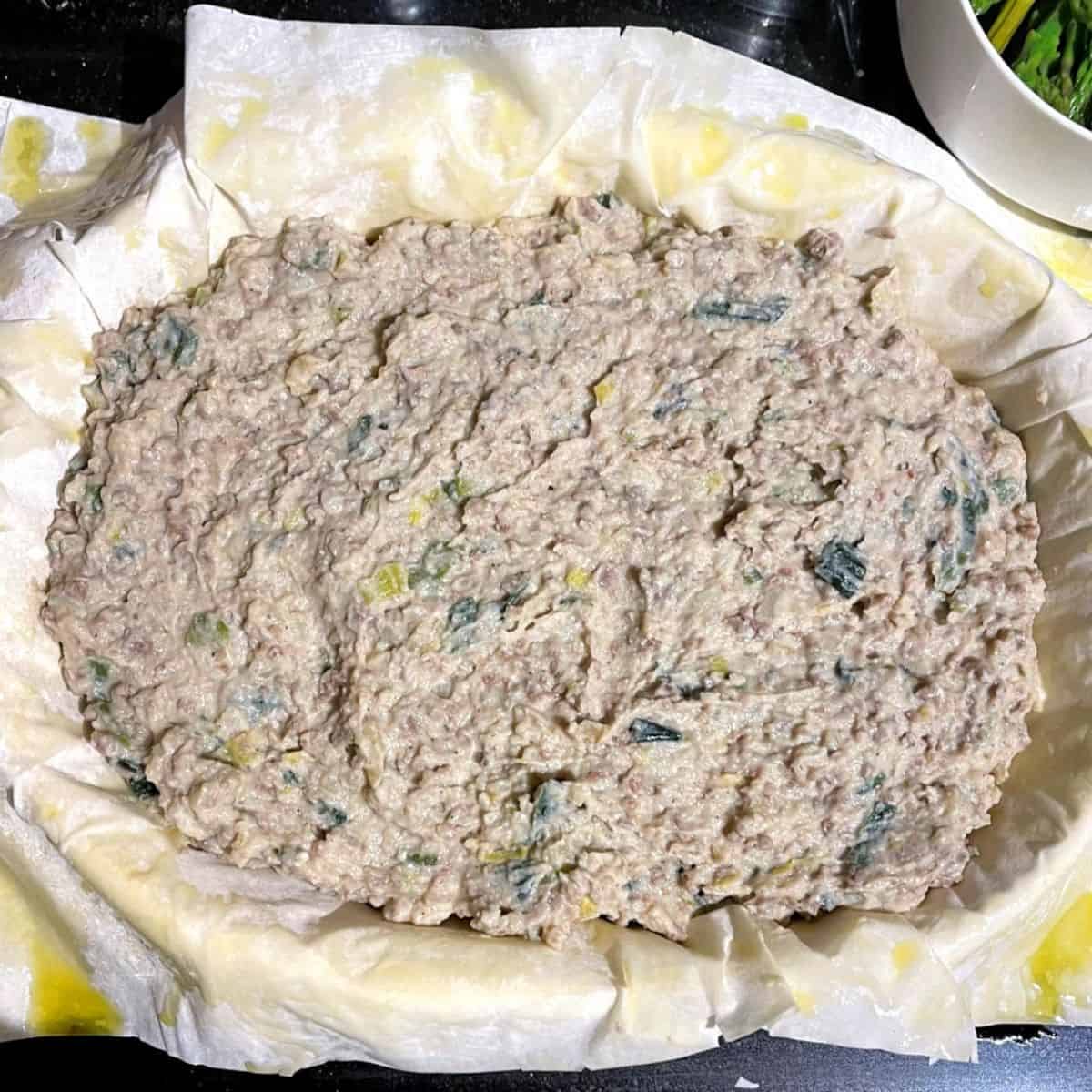 Mashed potato and vegan meat filling in filo pastry in baking dish.