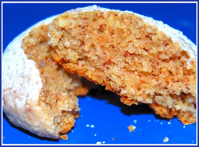 A broken amaretti cookie showing the soft center on a blue background