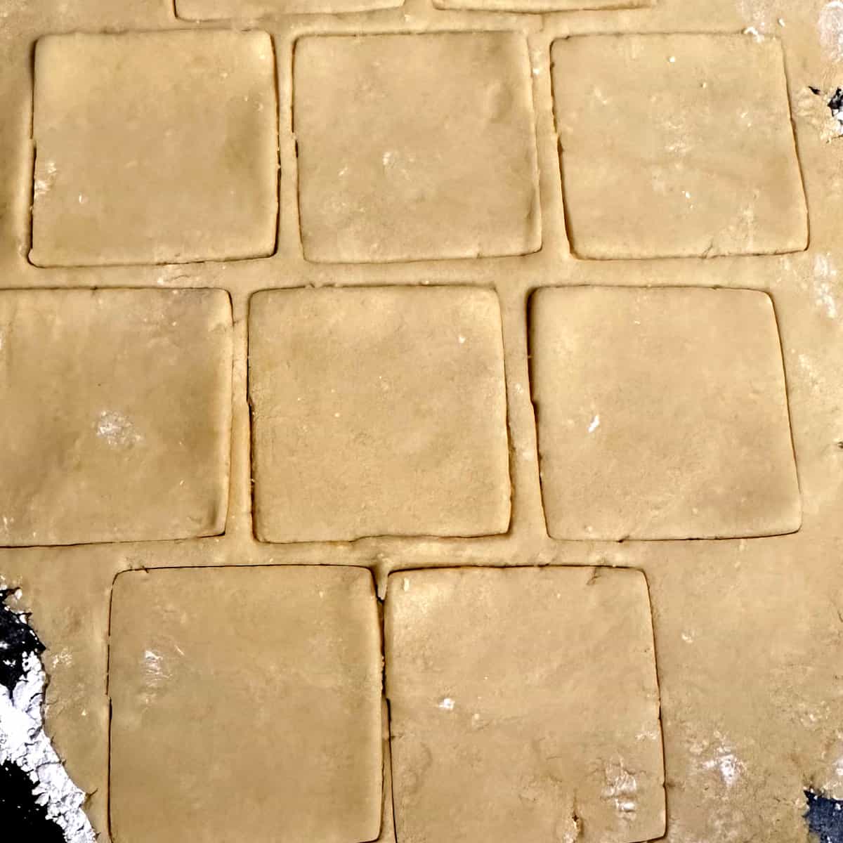Cookies cut out in squares from vegan lemon shortbread dough.