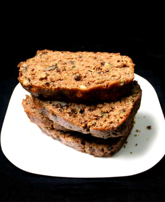 Photo of slices of vegan zucchini bread stacked on a white plate.