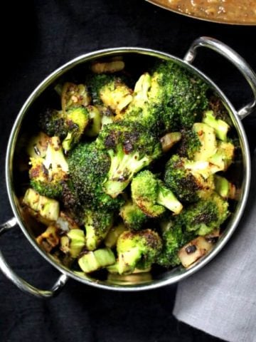 Green broccoli florets and stems stir-fried and served in a steel bowl