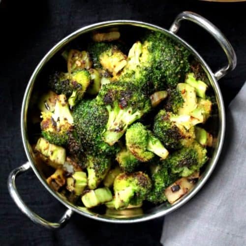 Green broccoli florets and stems stir-fried and served in a steel bowl