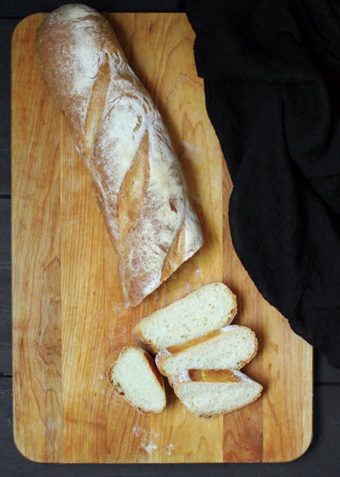 Sliced french bread loaf on a chopping board.