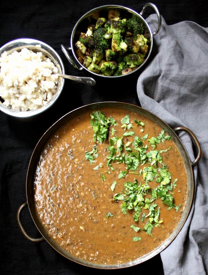 Top shot of spicy urad dal with brown rice and broccoli sabzi and a gray napkin