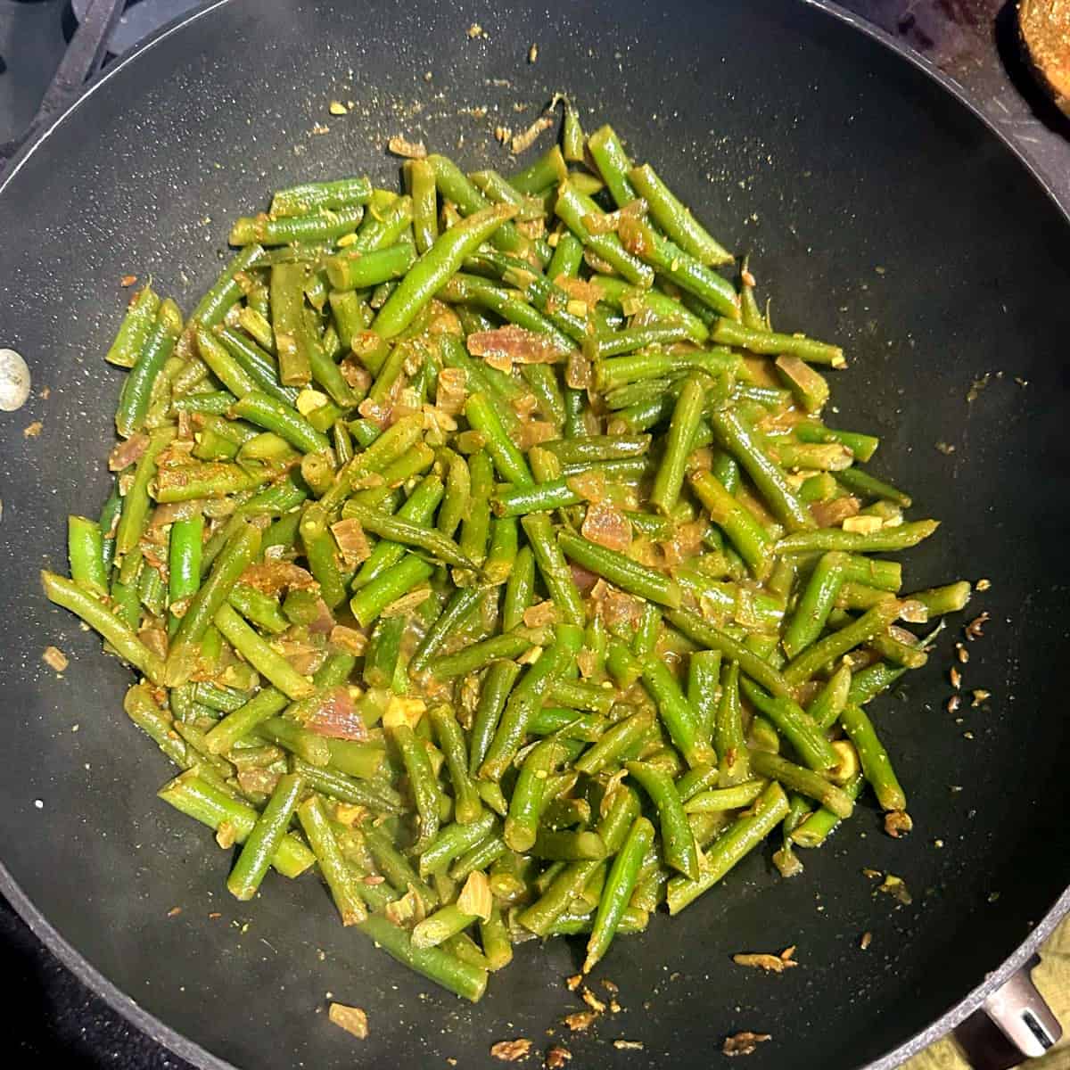 Cooked Trinidadian green beans curry in wok.