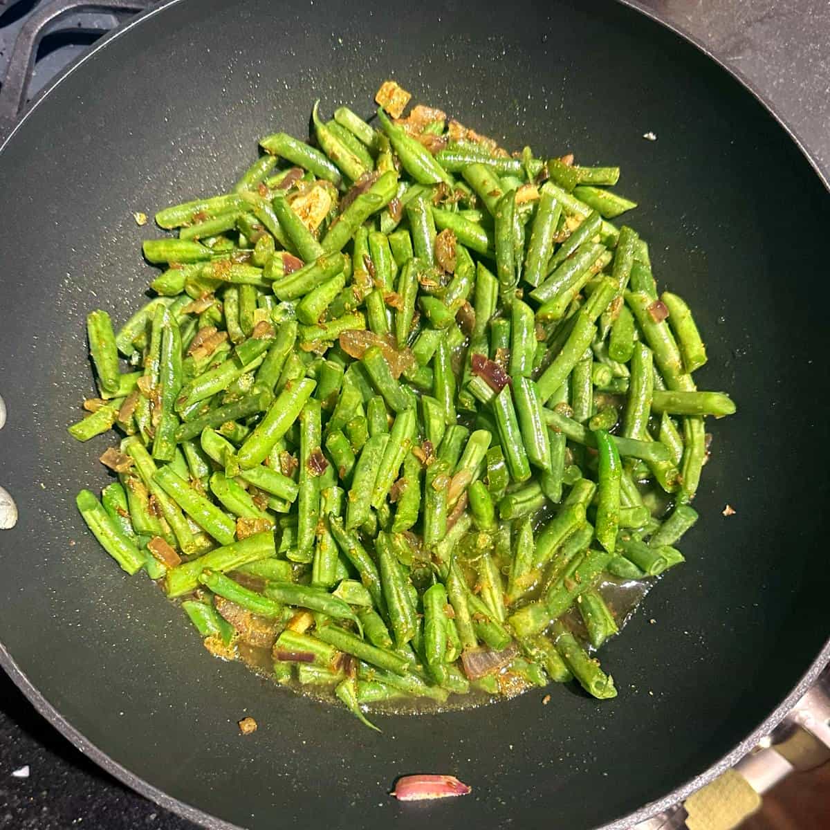 Green beans and stock added to wok for Trini green beans recipe.