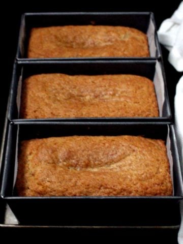 Front shot of three mini loaves of vegan, dairyfree and eggless mawa cakes on a baking sheet