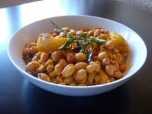 A white bowl with Kerala style peanut curry with curry leaves and potatoes.