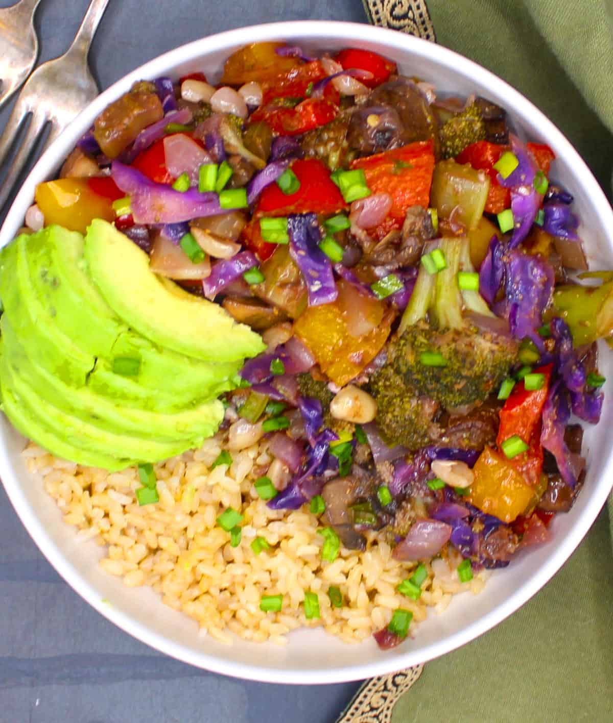 Kung pao veggies in bowl with brown rice and avocado.