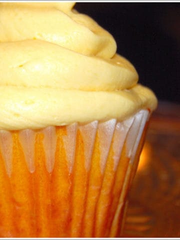 Closeup of a vegan mango cupcake piled high with mango buttercream frosting