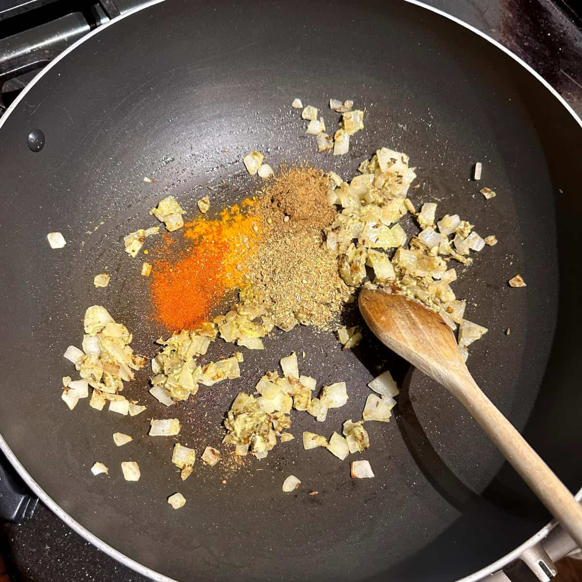 Spices added to onions and garlic in wok.