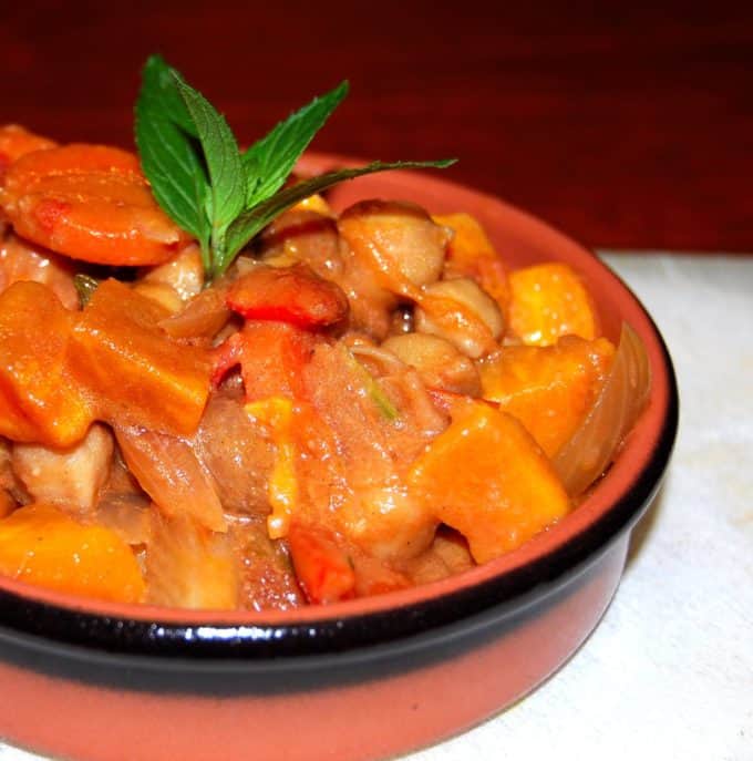 African Peanut Sweet Potato Stew in an earthenware bowl with a black rim on a white tablecloth.