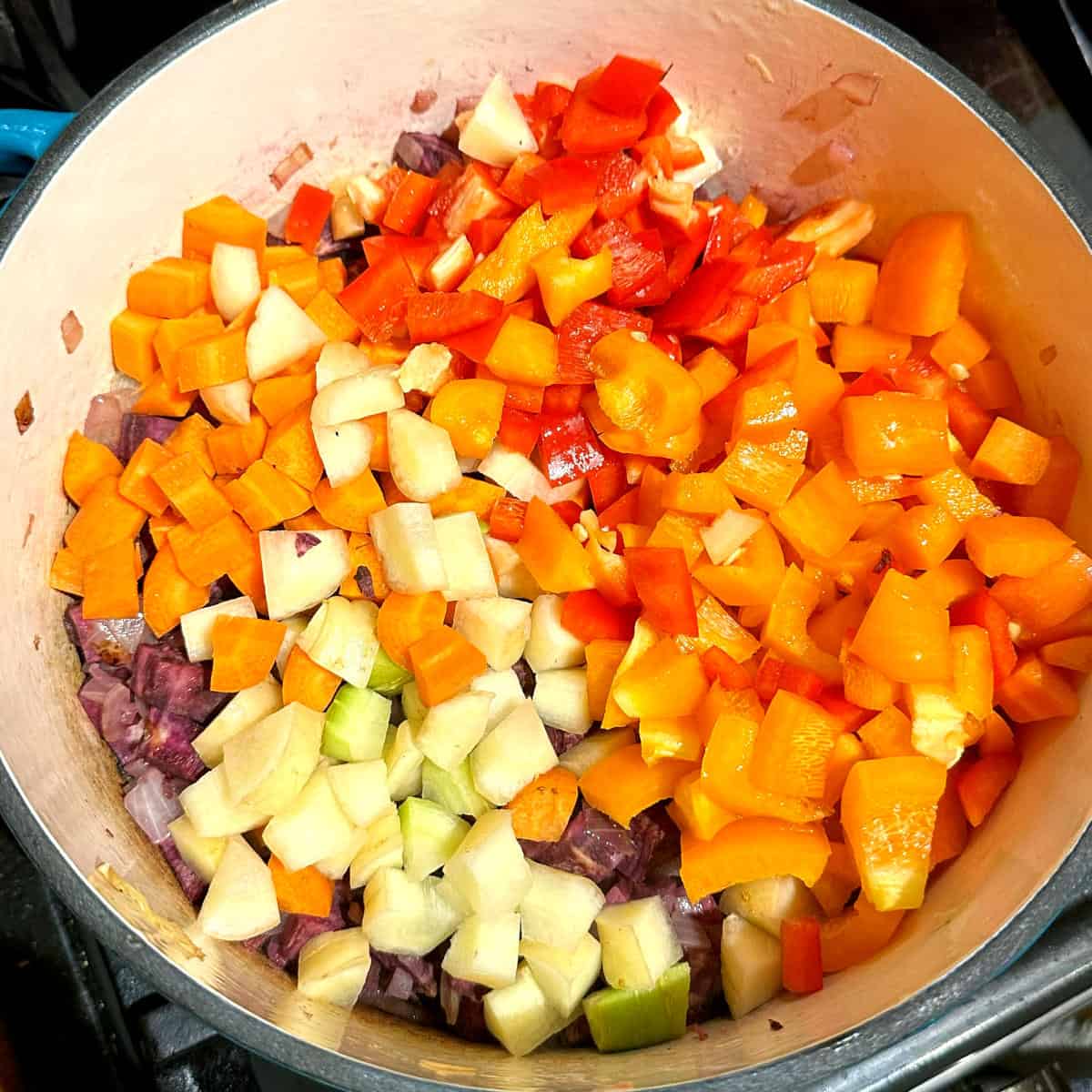 Carrots, bell peppers added to pot with sweet potatoes and onions.
