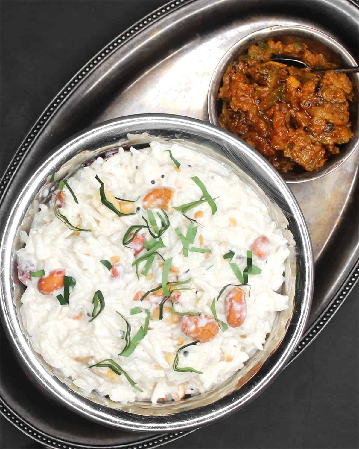 Vegan curd rice in copper and steel bowl with mango thokku pickle on the side.