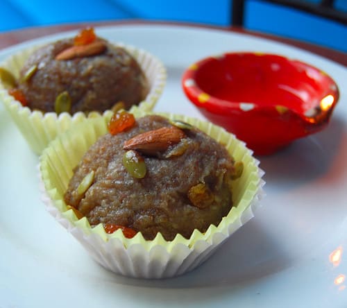 Photo of vegan almond halwa in paper cups with almonds, pumpkin seeds and raisins.