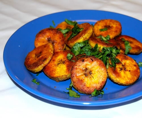 Roasted plantains in a blue ceramic dish with cilantro garnish