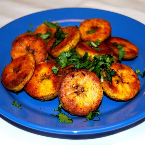 Roasted plantains on a blue plate with cilantro