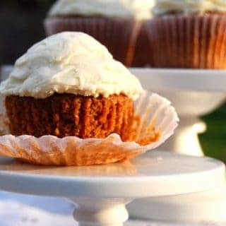 Vegan Irish cream cupcake on a small cake stand with more cupcakes in background.