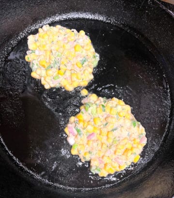 Corn fritters frying in cast iron skillet