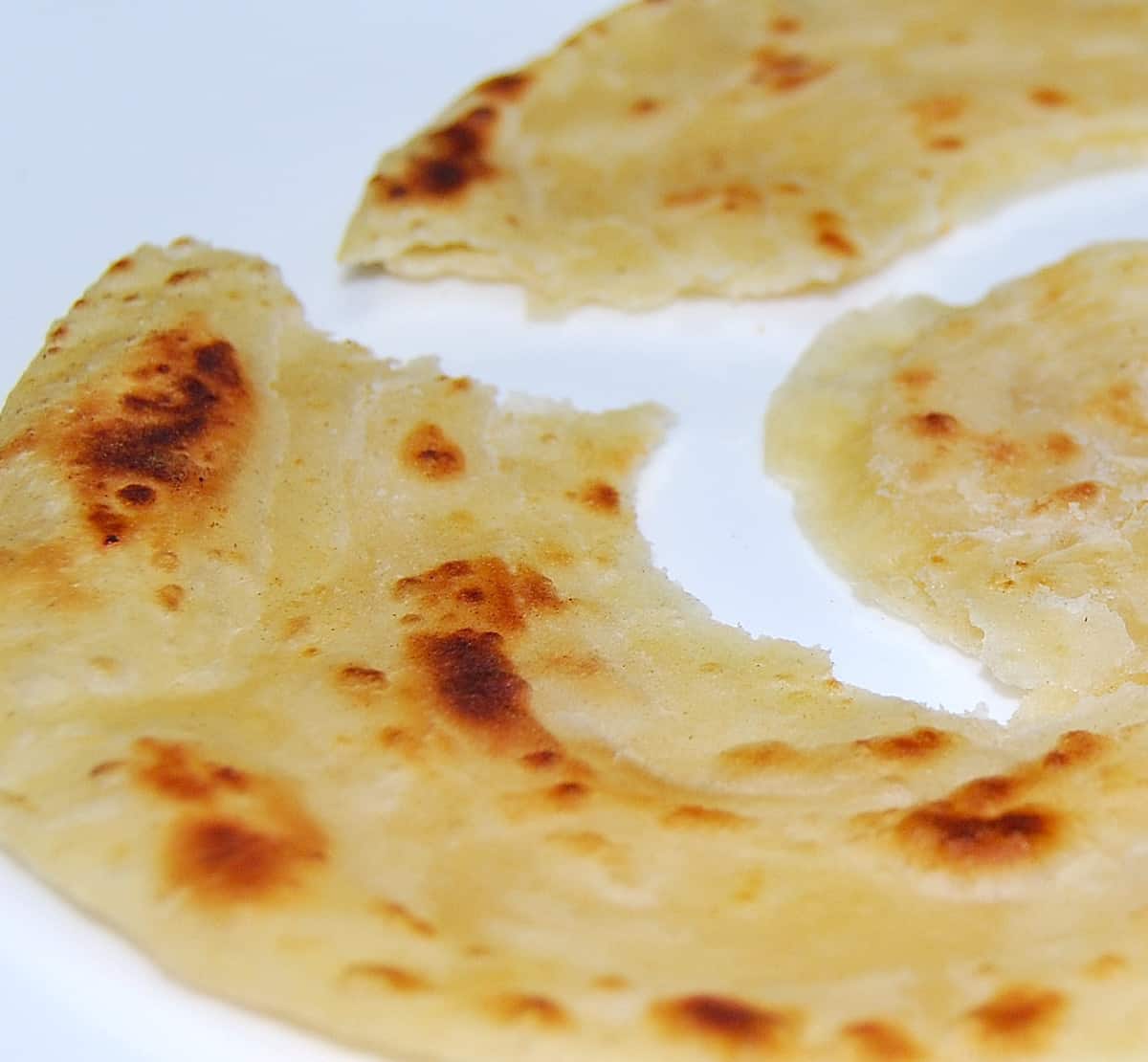 Khasta Paratha, torn up to show the layers, in a white plate