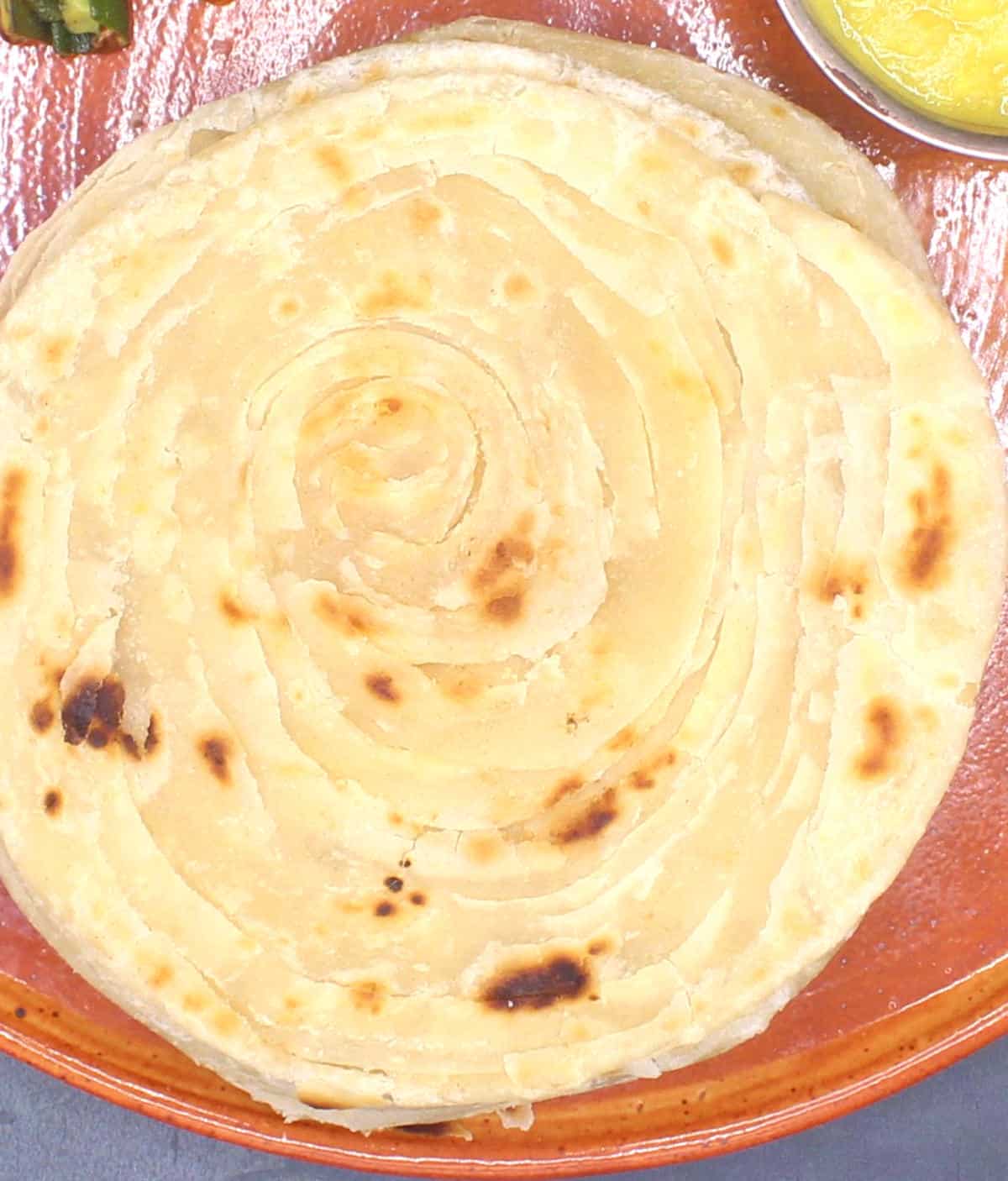Flaky paratha or parotta in clay plate.