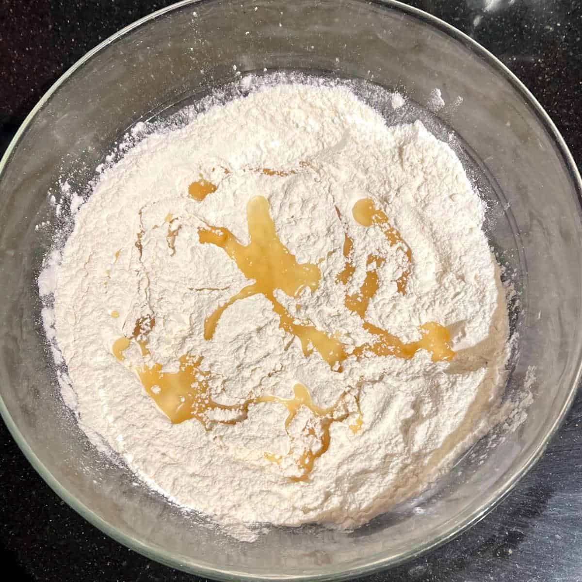 Oil drizzled over flour in bowl.