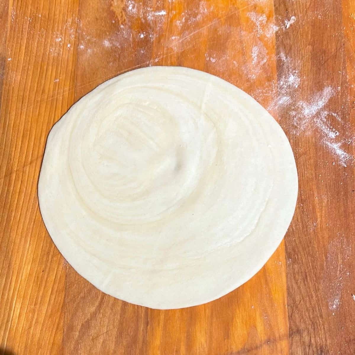 Paratha after rolling on wooden board.