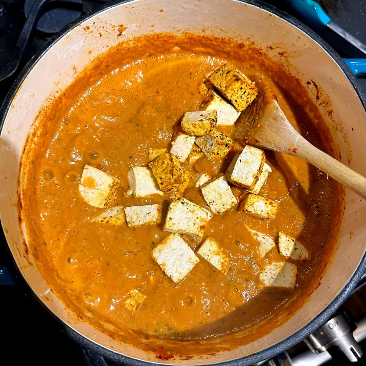 Tofu cubes added to the makhani sauce in pot.