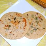 Two pieces of brown rice uthappam in white plate.