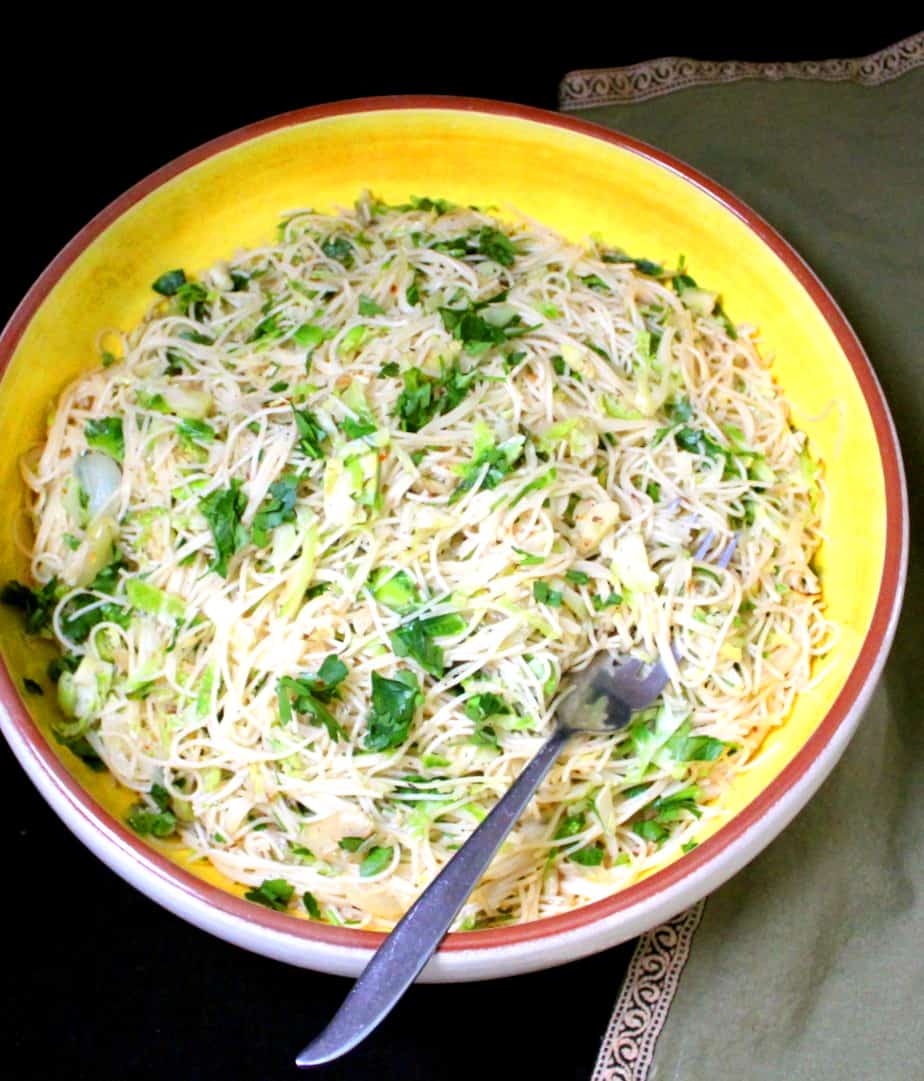 Vegan spaghetti with Brussels sprouts in large yellow and white pasta bowl with spoon.