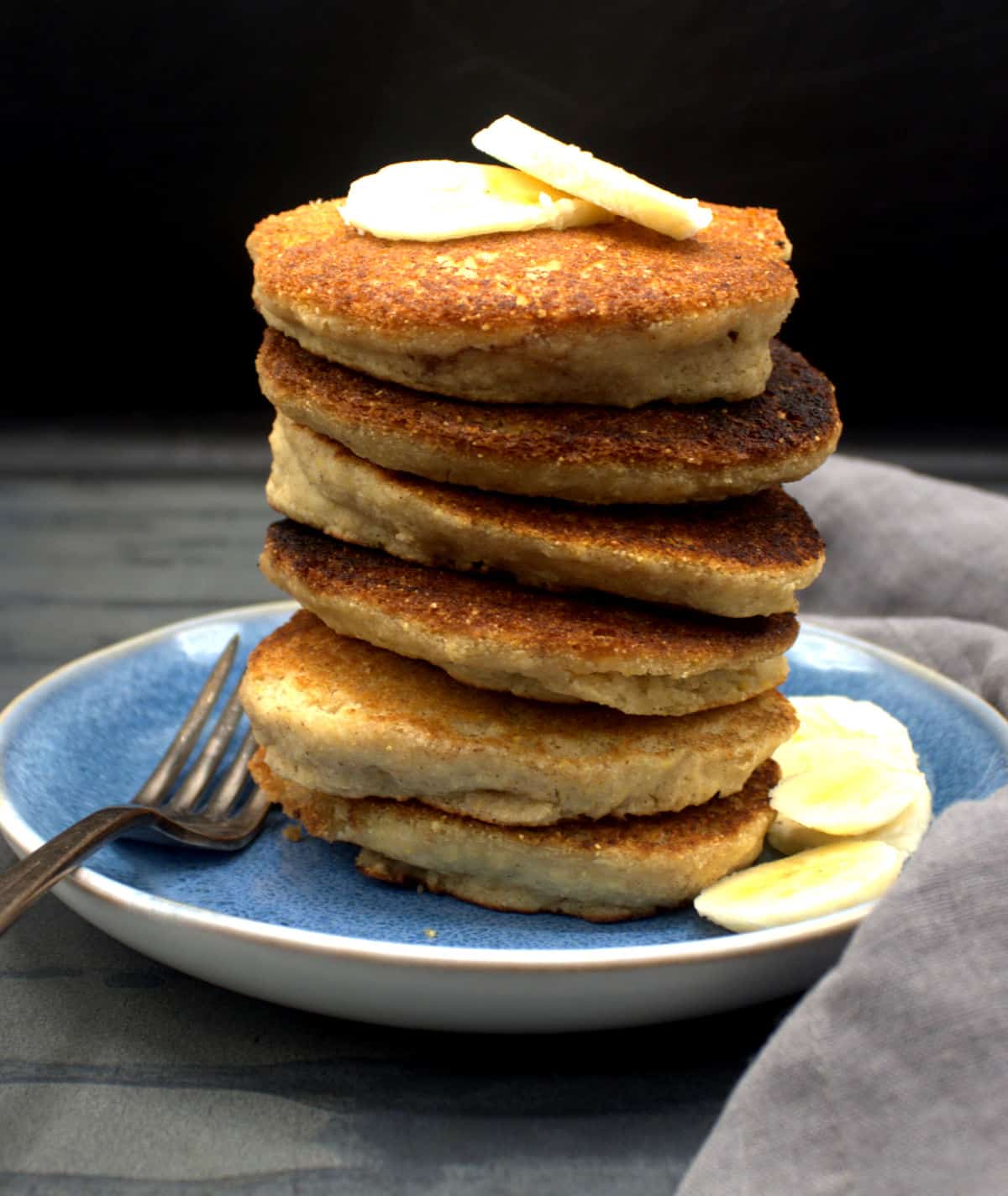 Vegan gluten-free multigrain pancakes stacked on a plate with banana slices.