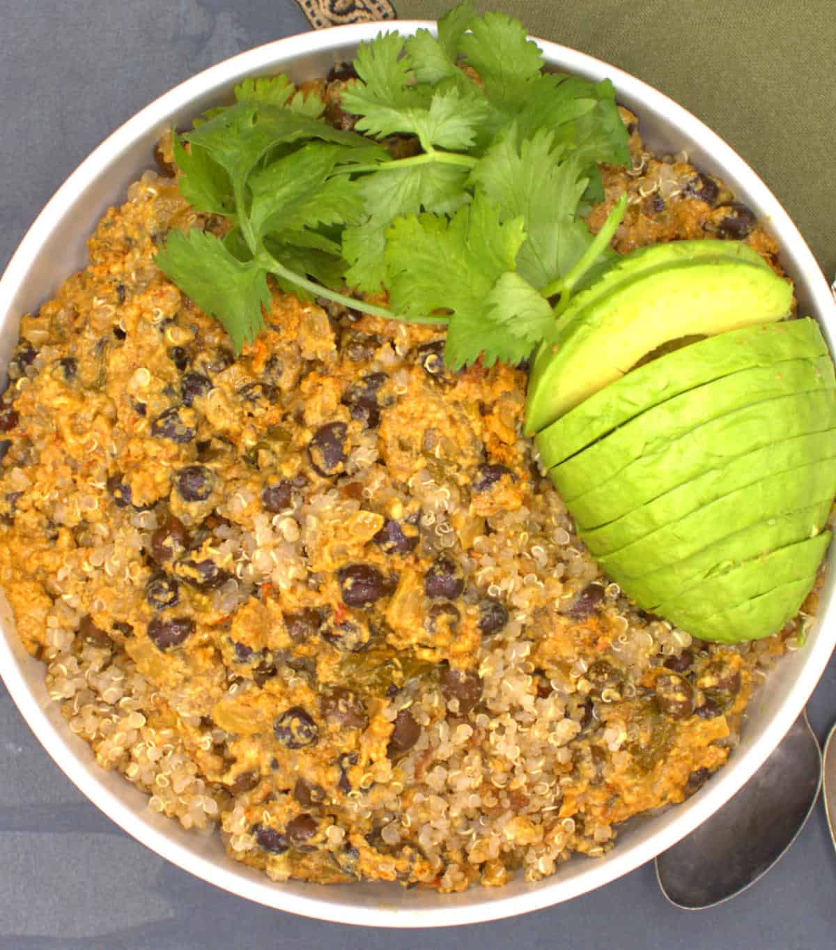 Quinoa biryani in bowl with avocado and cilantro.