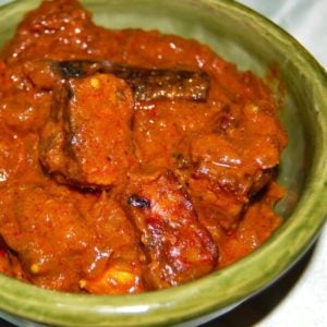 Vegan rogan josh with spicy red sauce in green bowl.