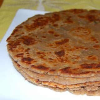 Arbi parathas stacked in white plate.
