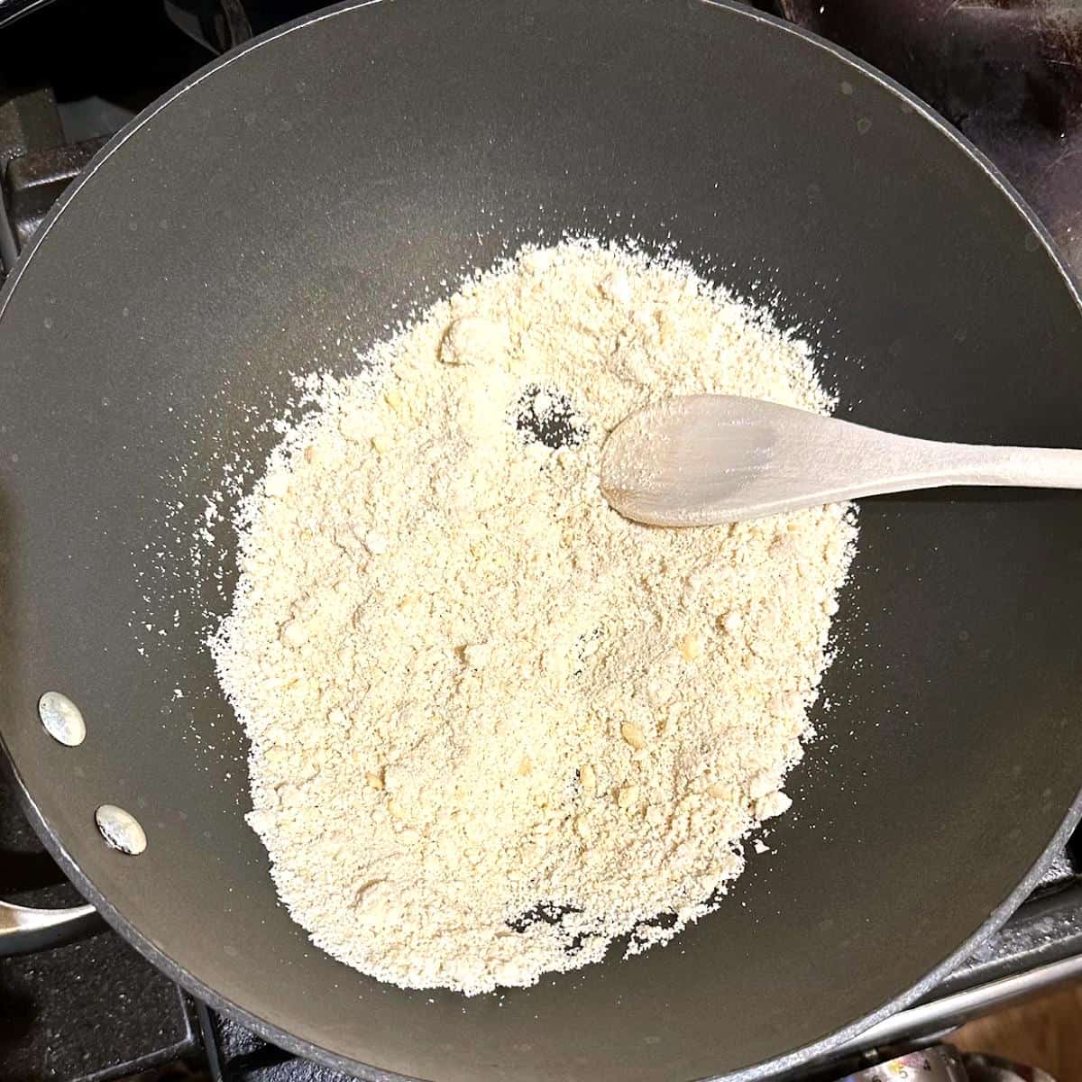 Cashew powder roasting in wok for kaju katli.