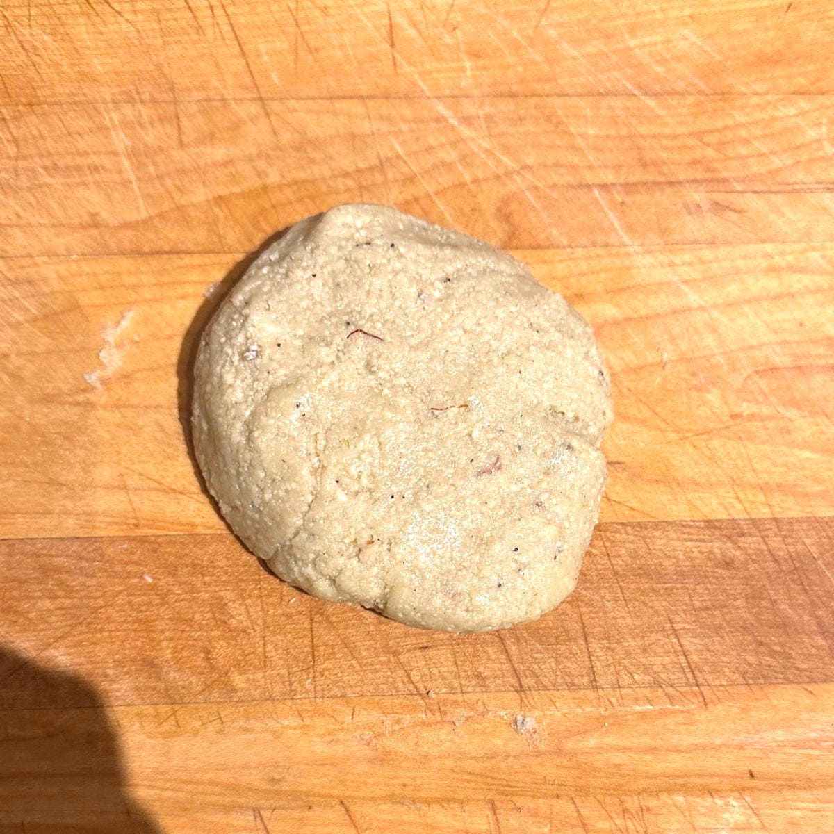 Kaju katli dough kneaded on wooden board.
