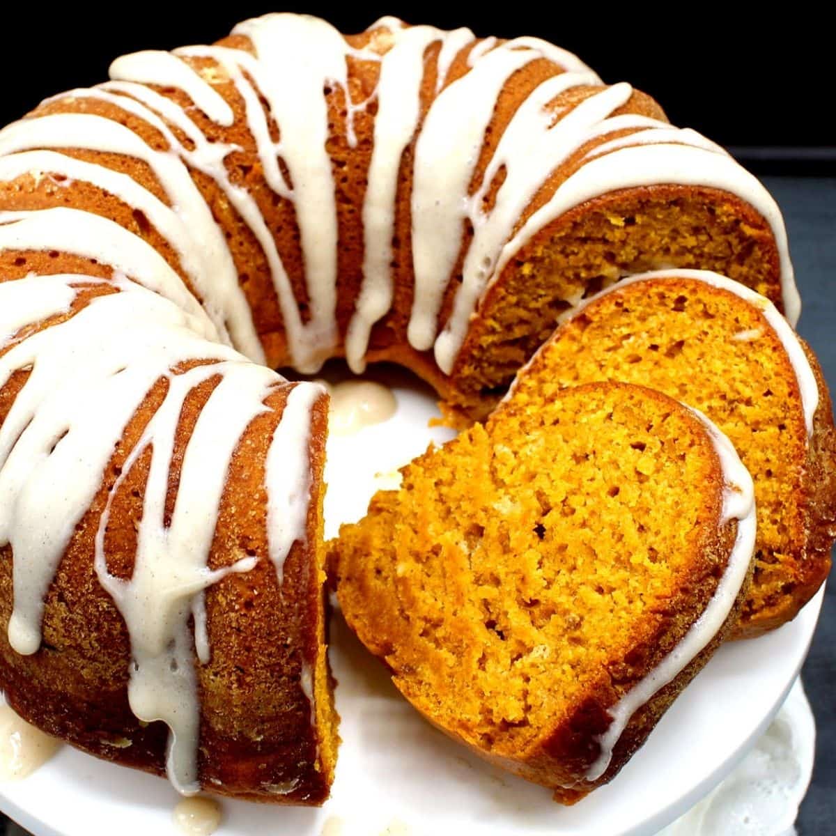 Closeup of vegan pumpkin cake with chai spices and cream cheese glaze with two slices cut
